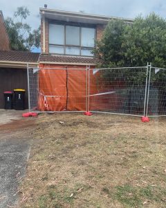 Emergency temporary fencing with orange tarp at residential property