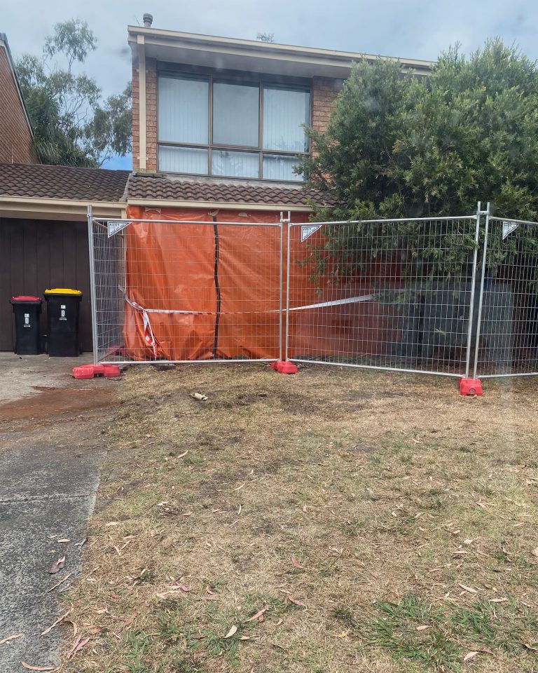 Emergency temporary fencing with orange tarp at residential property