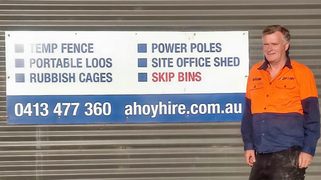 William next to Ahoy Hire sign listing construction services.